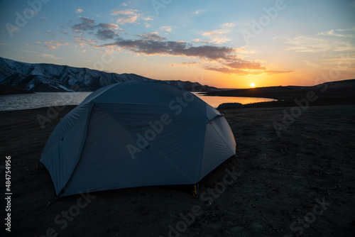 Tent on the beach. Camping in the mountains near the lake at the sunset.