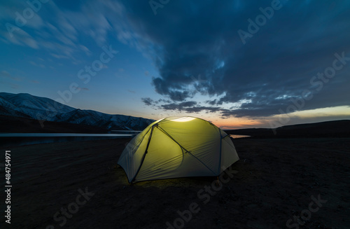 Tent on the beach. Camping in the mountains near the lake after sunset.