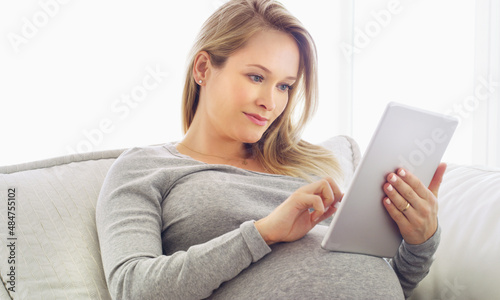 Getting some online pregnancy tips. Shot of a pregnant woman using a tablet at home.