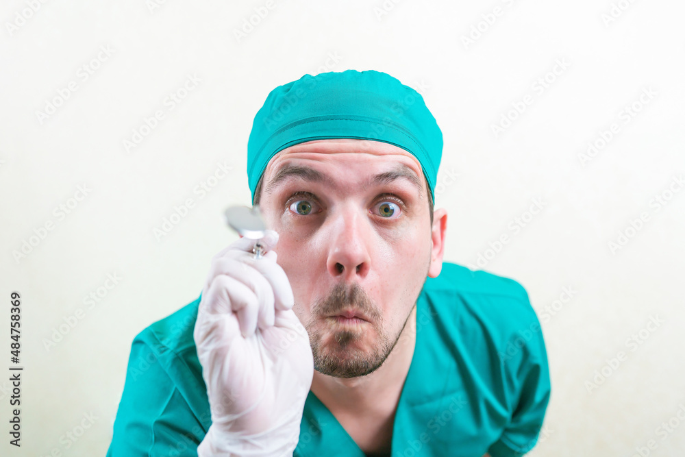 Funny inspecting doctor in green suit with laryngeal mirror defocused in his hand close up isolated. selective focus, Funny inspecting doctor in green suit with laryngeal mirror defocused in his hand close up isolated. selective focus,