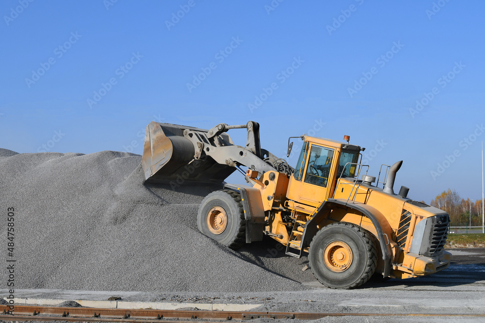 Heavy loader is working on construction or quarry, moving gravel gravel. 