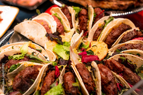 Assortment of homemade beef tacos with lettuce, ready for sale to tourists at the market stall photo