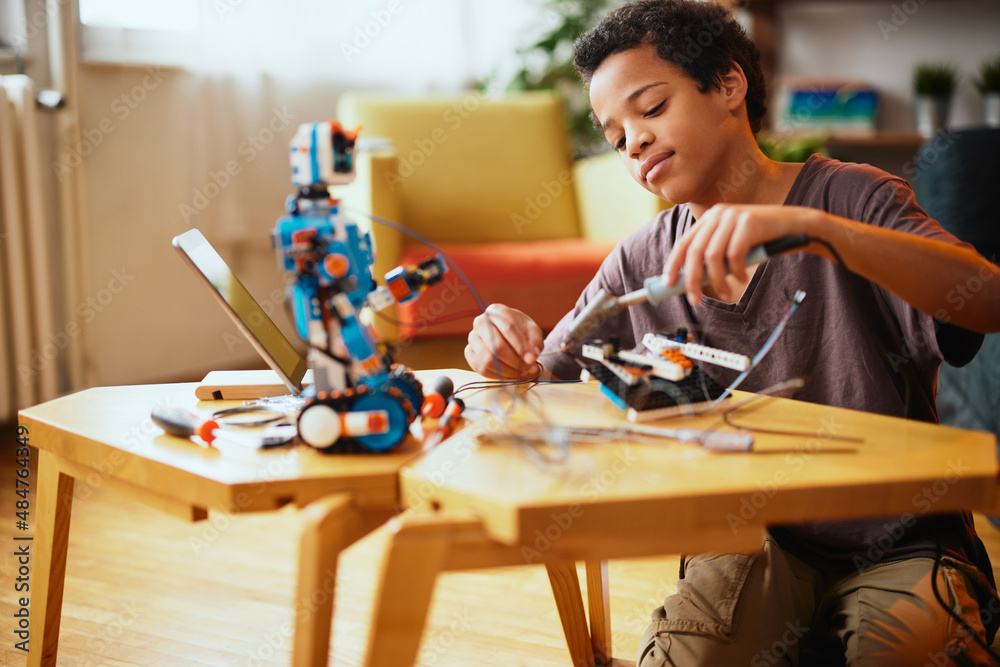 Fototapeta premium An African-American boy making a robot at home. Education in robotic at home.