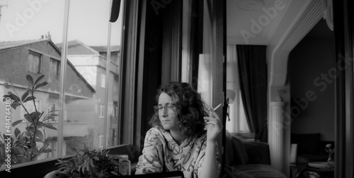 Girl with cigarette looking through the window