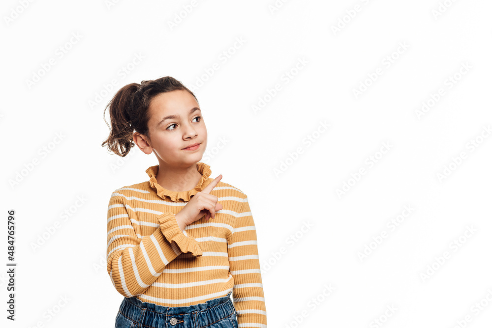 Young girl pointing to the side and showing something while standing on an isolated white background. Advertising and promotion concept. Young girl pointing to the side and showing something while standing on an isolated white background. Advertising and promotion concept.