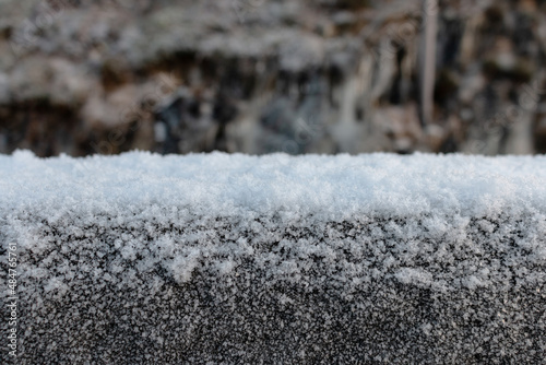 Snow on a concrete fence close-up. Blurred background. Winter in Norway