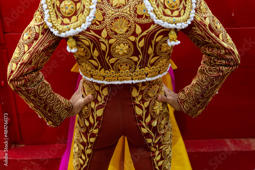 Spanish bullfighter's costume seen from behind in a bullfight. Bullfighting cape in the hands of a matador dressed as a bullfighter.