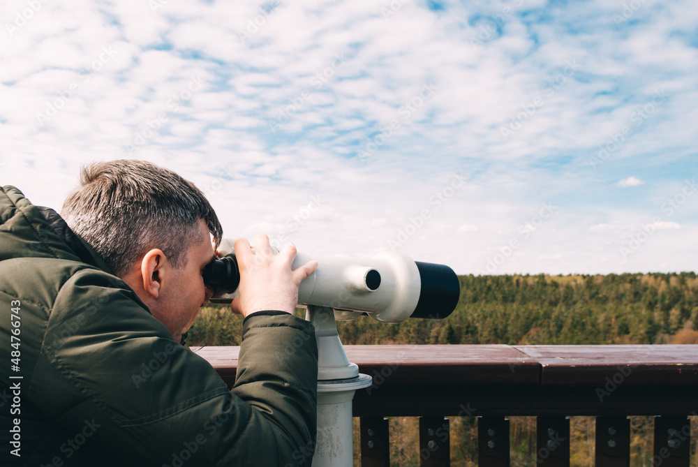 Obraz premium Man looks into the distance from observation deck, using Tower viewer