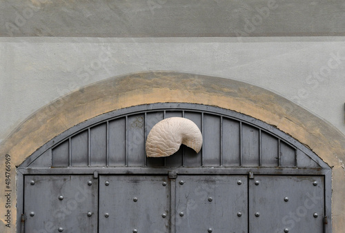 Detail of the exterior of an old building with a metal studded door decorated with a Nautilus shell, Sanremo, Imperia, Liguria, Italy