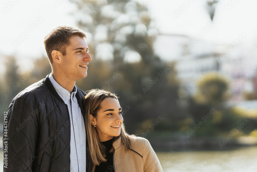 Woman leans against her boyfriend's chest while smiling Woman leans against her boyfriend's chest while smiling