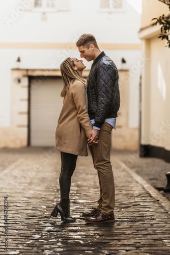 woman stands on tiptoe to try to kiss her boyfriend photo