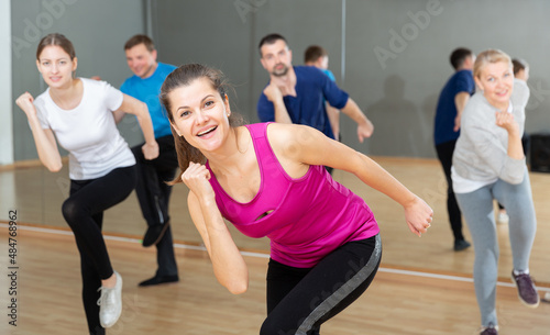 Young smiling woman practicing vigorous lindy hop movements in dance class