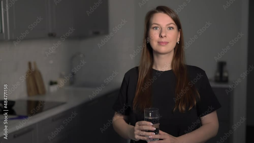 A young woman is holding a glass of clean water. The girl drinks water. A young woman is holding a glass of clean water. The girl drinks water.