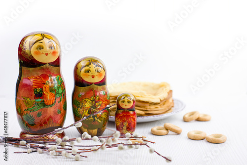 Photos Background with pancakes, wooden dolls matryoshka, sushki and pussy-willow on white for Maslenitsa festival