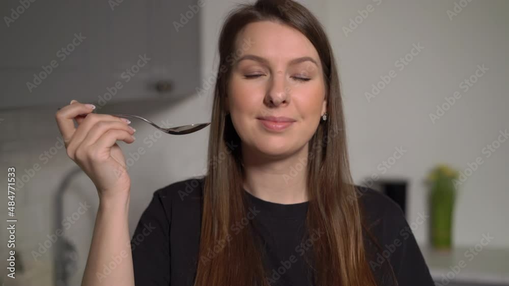 A young woman is cooking soup in the kitchen. Girl opens lid of pot and try food A young woman is cooking soup in the kitchen. Girl opens lid of pot and try food
