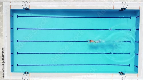 Persona nadando de una lado a otro de la piscina vacía. Agua clara. Fondo azul photo
