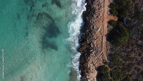 Recorrido por una preciosa cala ubicada en la isla de Palma de Mallorca. Agua de colores azules claros turquesas, olas rompiendo contra las rocas. Sendero al lado de la costa donde poder caminar. photo