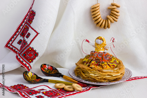 Background with pancakes, textile doll, wooden spoon, rushnik and sushki for Maslenitsa festival. photo