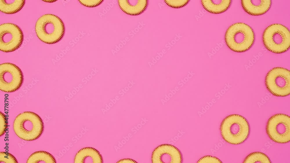 Moving biscuit cookies frame for text on vibrant pink theme. Stop motion flat lay