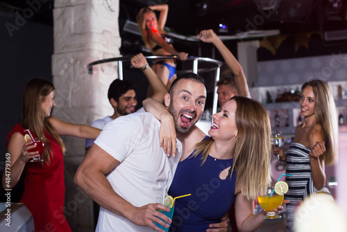 portrait of couple of female and male with cocktails dancing in the night club