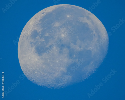 Closeup of Craters and Peaks on the Surface of a Blue Moon against a Clear Blue Sky