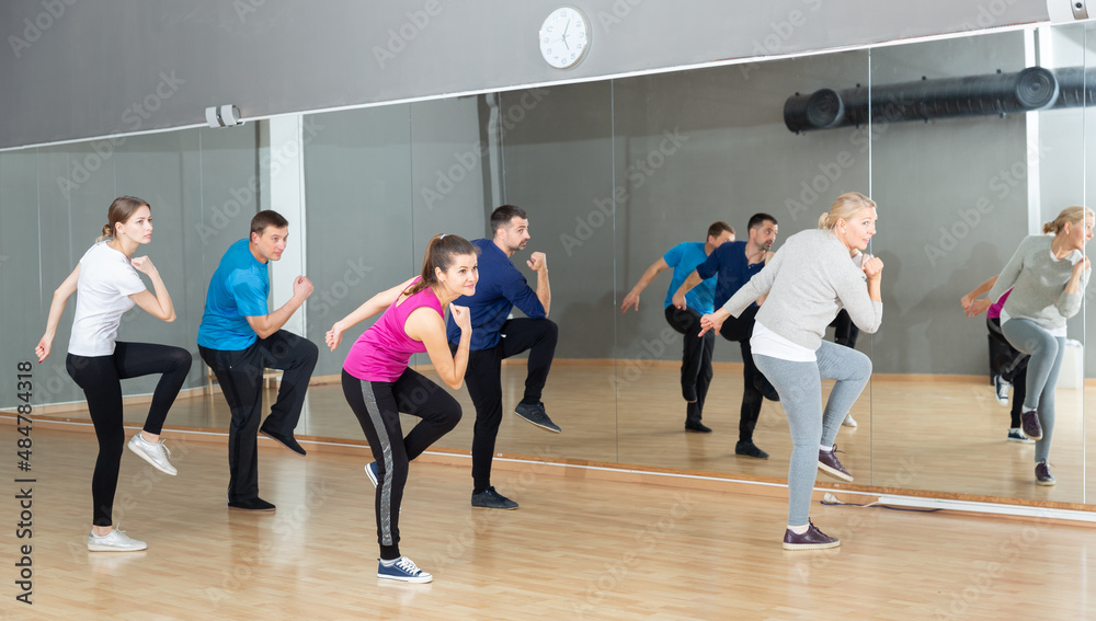 Portrait of dancing people practicing vigorous swing during group training in dance studio