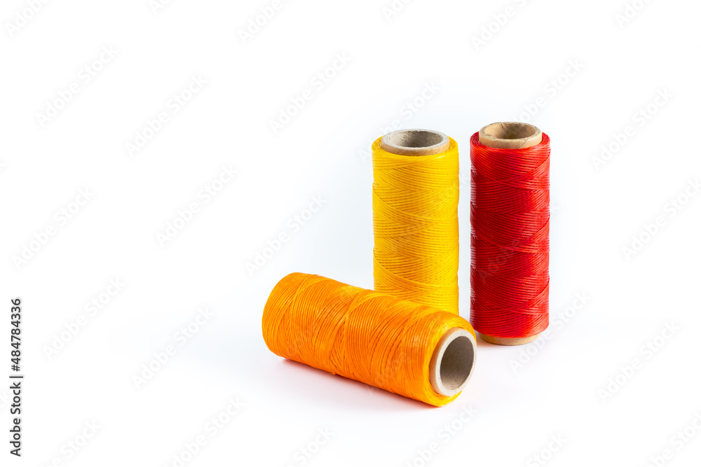 A skein of red, orange and yellow thread. Coils of colored threads on a white background. Waxed sewing thread for leather goods. A skein of red, orange and yellow thread. Coils of colored threads on a white background. Waxed sewing thread for leather goods.