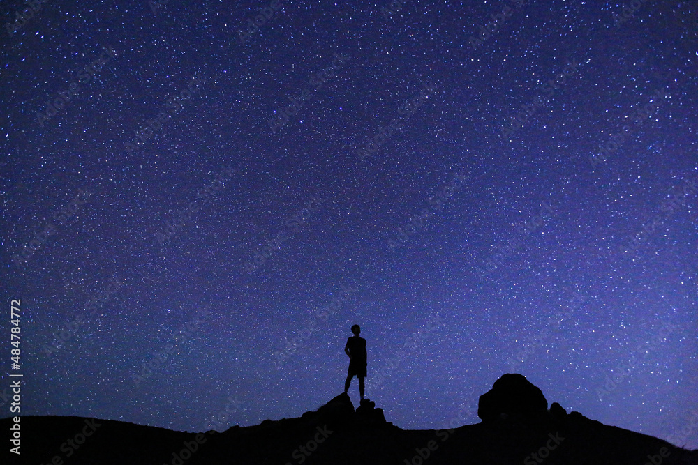 Silhouette of  men / boy on the hill.  Stargazing at Oahu island, Hawaii. Starry night sky, Milky Way galaxy astrophotography.
