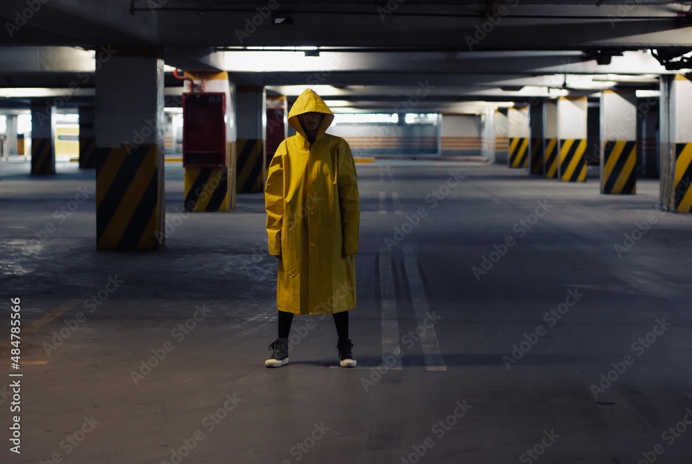 Unrecognizable woman wearing a raincoat in an underground parking lot