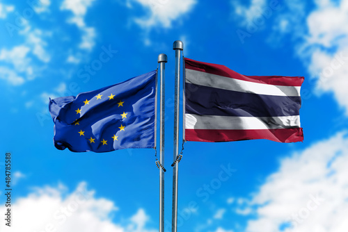 Flags of European Union and Thailand on the wind against blue sky