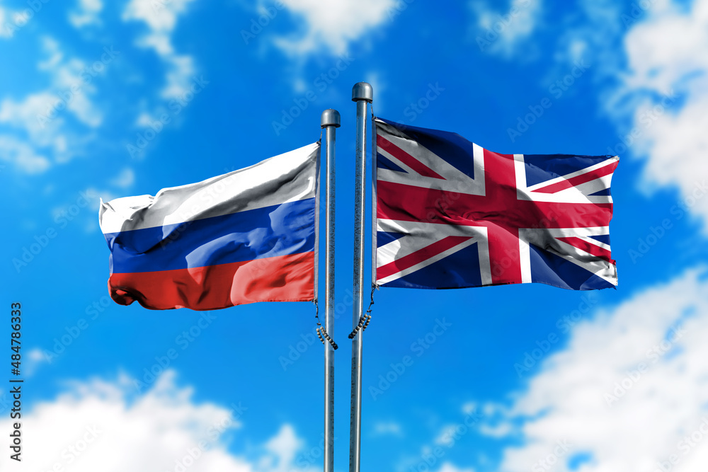 Flags of Russia and United Kingdom on the wind against blue sky