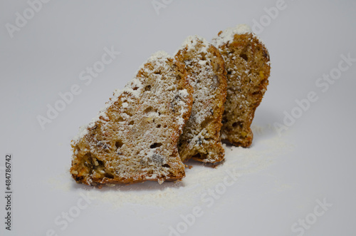 Spicy carrot, nuts and cinnamon loaf sliced cake decorated with powdered sugar on a paper.,3 pieces of slided cake
