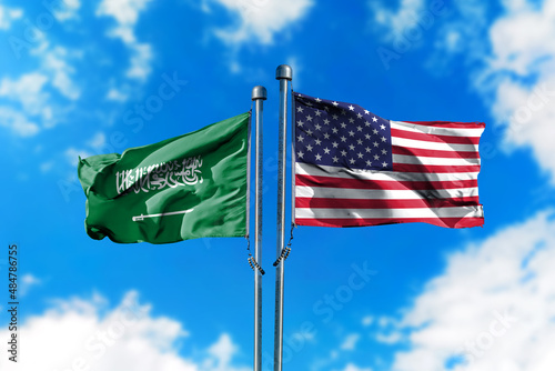 Flags of Saudi Arabia and America on the wind against blue sky