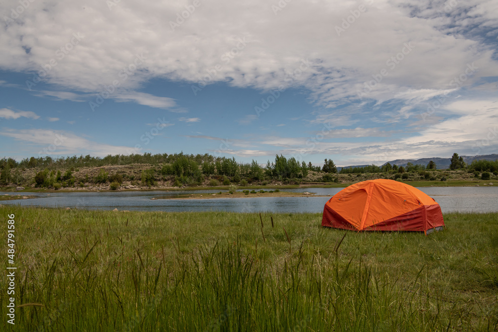 an orange tent by a lake