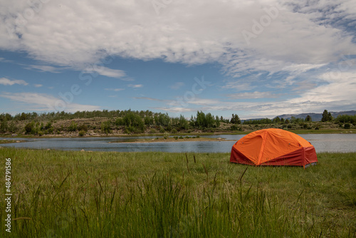 an orange tent by a lake photo