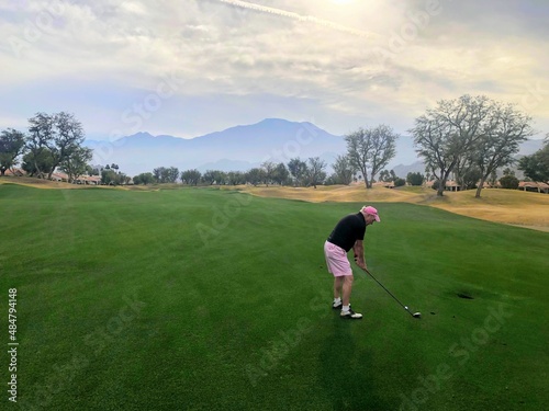 A man lining up his shot on a fairway with his three wood on a beautiful par 4 in palm springs, california, USA
