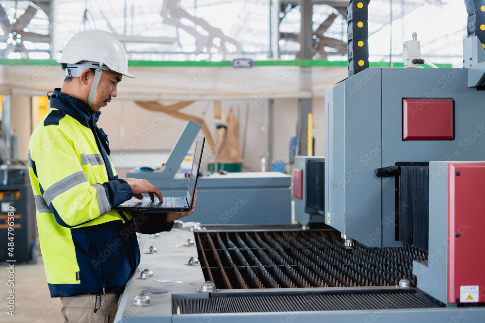 Fototapeta premium Asian male industrial engineer using laptop He made a gesture while working in a heavy industrial factory.