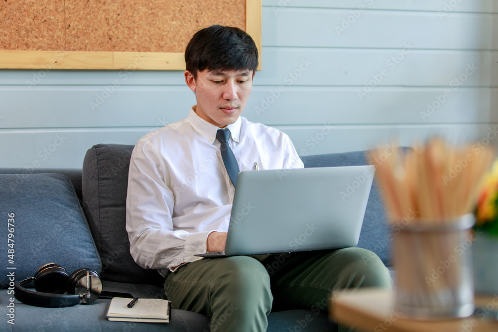 Young businessman working with laptop on resting couch of office lobby and close eyes to think solution about marketing strategy and planning network to solve difficult task. Young businessman working with laptop on resting couch of office lobby and close eyes to think solution about marketing strategy and planning network to solve difficult task.