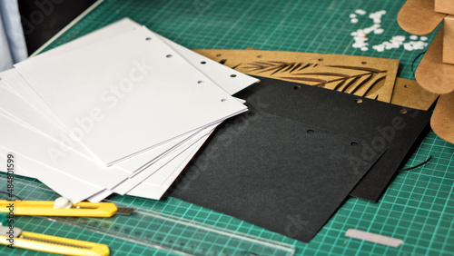 Paper with holes of hole puncher on table in warehouse. Punched paper. Paper for making notebook with interchangeable blocks on rings  hand-assembled