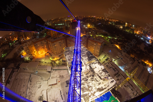 luminous crane in the city at night, construction of a new house, attraction to a construction company
