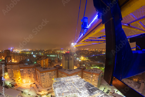 luminous crane in the city at night, construction of a new house, attraction to a construction company