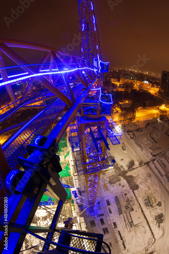 luminous crane in the city at night, construction of a new house, attraction to a construction company