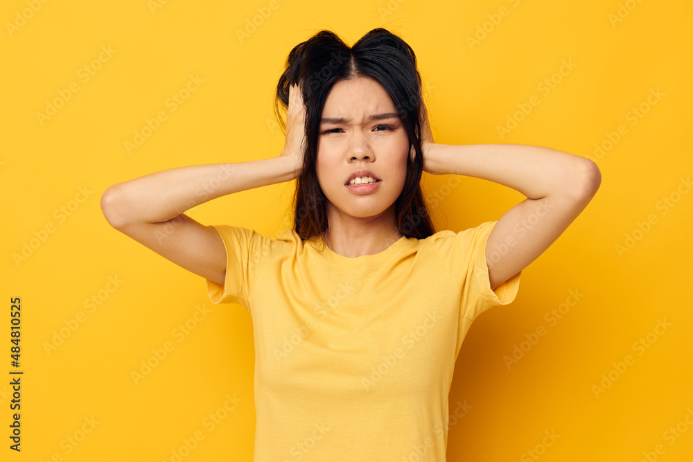 pretty brunette in a yellow t-shirt holding his head discontent yellow background unaltered pretty brunette in a yellow t-shirt holding his head discontent yellow background unaltered