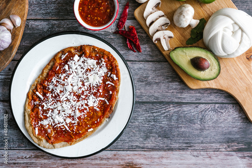 Memela sope quesadilla poblana of red sauce with cheese, onion and avocado traditional mexican food from Puebla, Mexico photo