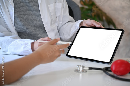 Close up view doctor holding digital tablet and explaining diagnosis to her patient.