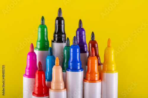 Several colored markers without protective caps on a yellow background © Max Zolotukhin