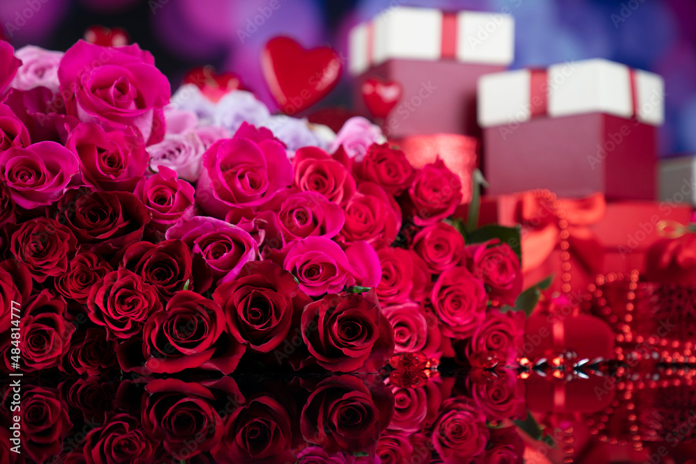 Valentines day theme. Gifts in boxes, red hearts and big bouquet of natural roses on blue bokeh background.
