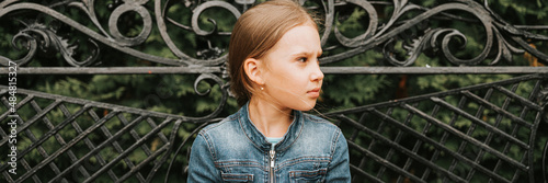 thoughtful scowl candid eight year old kid girl sits on bench and observe nature. prepubertal age of children and lives, mind psychology and mental health. fashion clothes. geometric shapes. banner photo