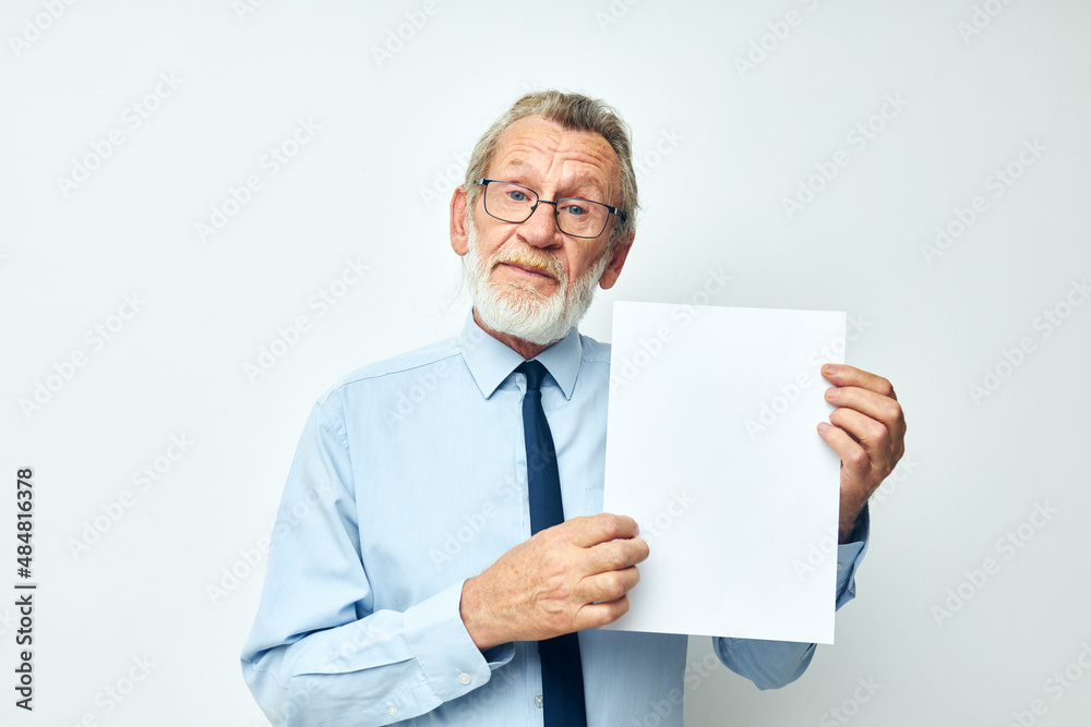 Photo of retired old man holding documents with a sheet of paper light background Photo of retired old man holding documents with a sheet of paper light background