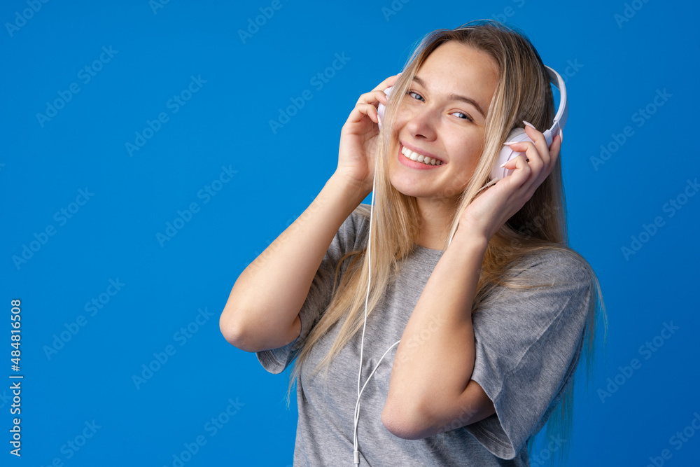 Happy young woman with headphones on a blue background Happy young woman with headphones on a blue background